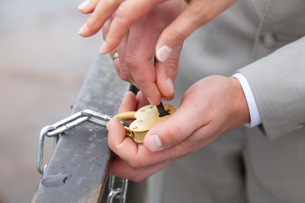 The bride and groom's hands close the heart-shaped lock. signs at the wedding. High quality photo