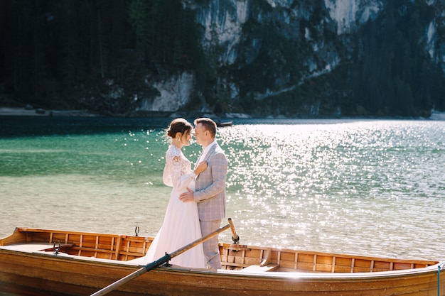 Bride and groom sailing in wooden boat, with oars at Lago di Braies lake in Italy