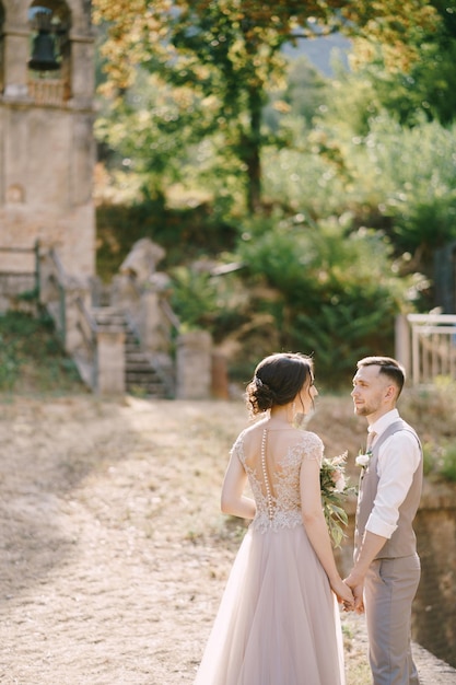 Bride and groom stand against the background of a small chapel