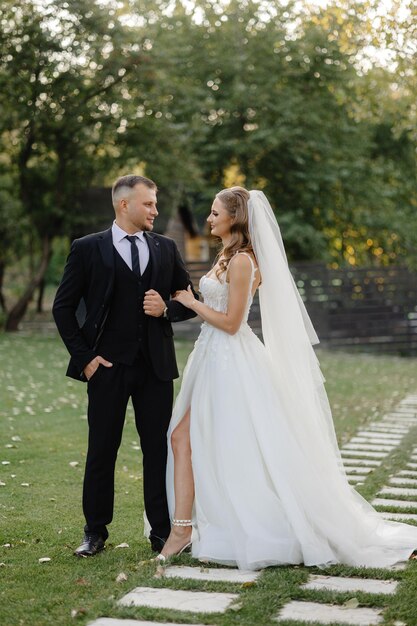 a bride and groom stand in a garden