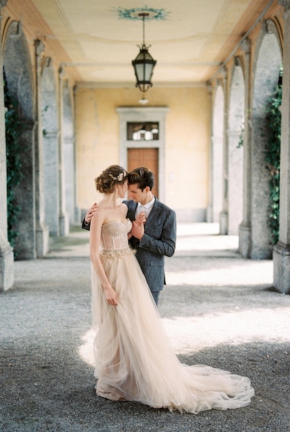 Bride and groom stand hugging on the terrace of an old villa