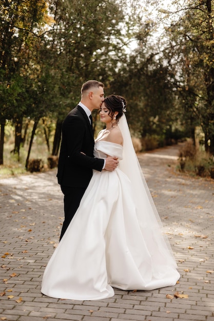 a bride and groom stand in a park