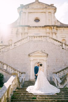 Gli sposi stanno sui gradini di pietra vicino all'antica chiesa