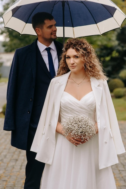 a bride and groom stand under an umbrella