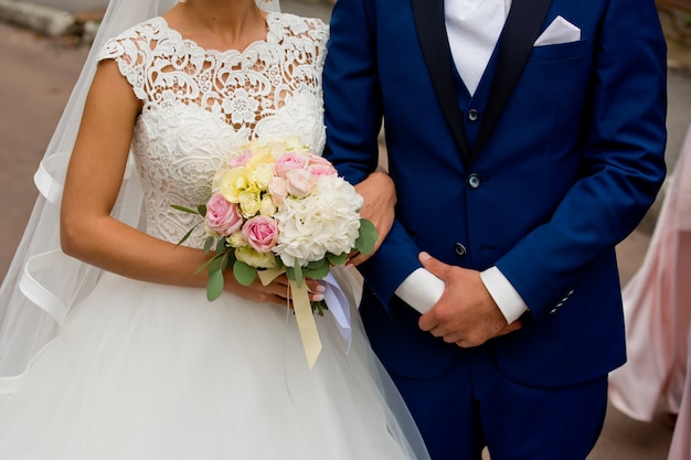 bride and groom stand with their hands together.