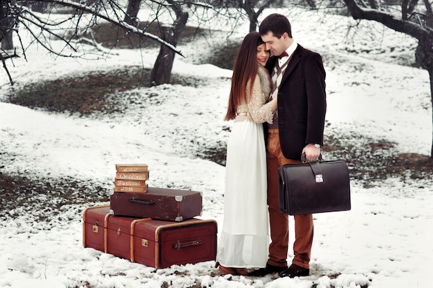 "Bride and groom standing with luggage outside"