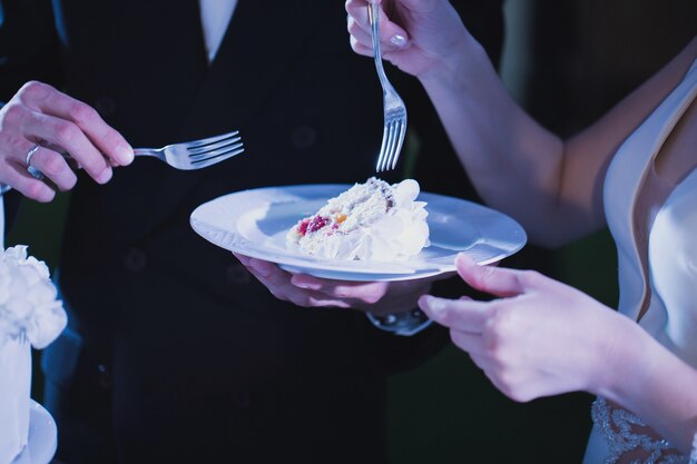 Bride and groom tasting luxury wedding cake decorated with roses