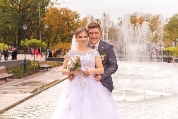 bride and groom together near the fountain are happy on their wedding day