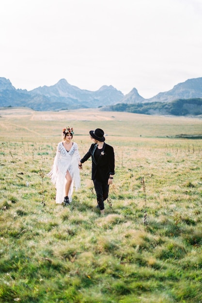 Bride and groom walk across the field holding hands