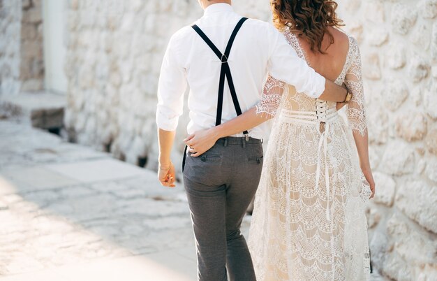 Bride and groom walk along the old pavements of the town bottom view