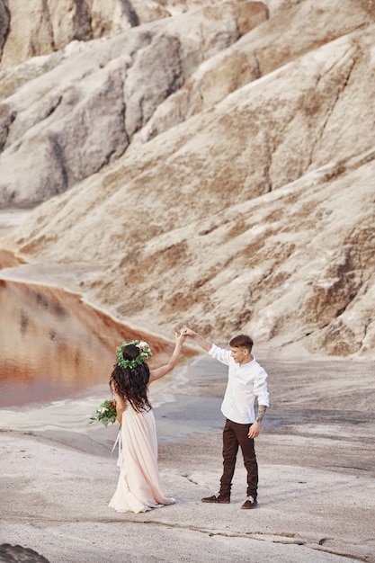 Bride and groom walk along the red mountains, fabulous scene. Couple in love