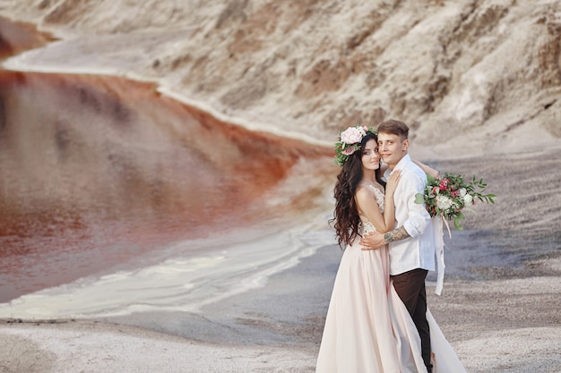 Bride and groom walk along the red mountains, fabulous scene. Couple