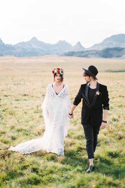 Bride and groom walk down the lawn holding hands