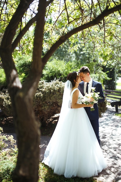 The bride and groom walk together in the park Pretty bride and stylish groom Wedding day Marriage