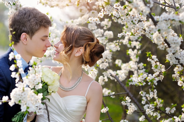 Bride and groom walking in the blossoming spring garden. Valentine dating