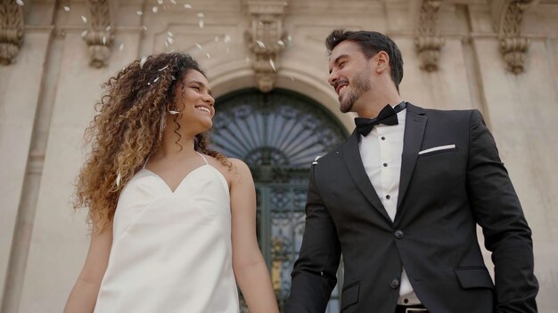 Bride and groom walking down while guests toss petals at wedding action wife and husband by the