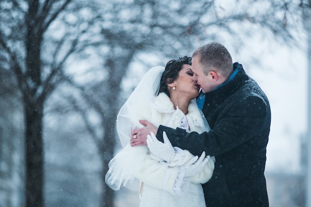 Bride and groom walking on the European city in the snow