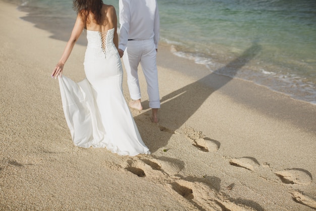 Bride and groom walking in the sand