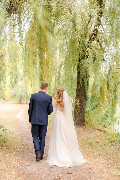 Bride and groom walking through the park