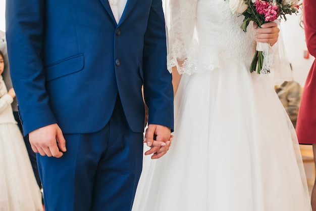 Bride and groom at the wedding ceremony holding hands