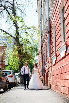 Sposa e sposo in abiti da sposa che camminano lungo le strade della città il giorno del matrimonio