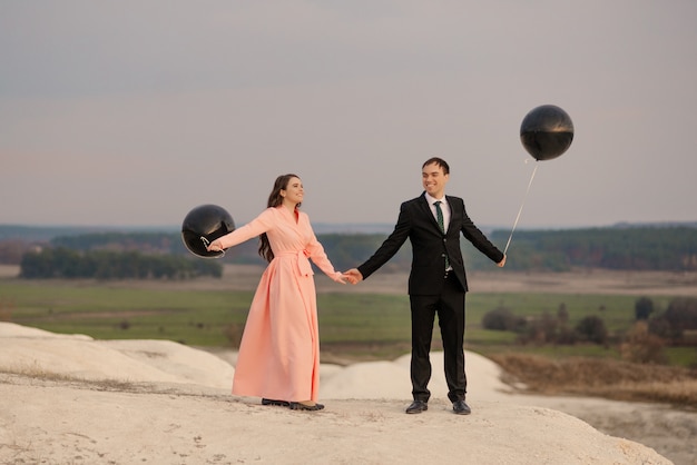 Bride and groom with large helium balloons at wedding walk enjoy each other outdoor with beautiful view at sunset