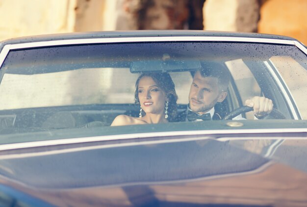 Bride and handsome groom embracing in stylish car