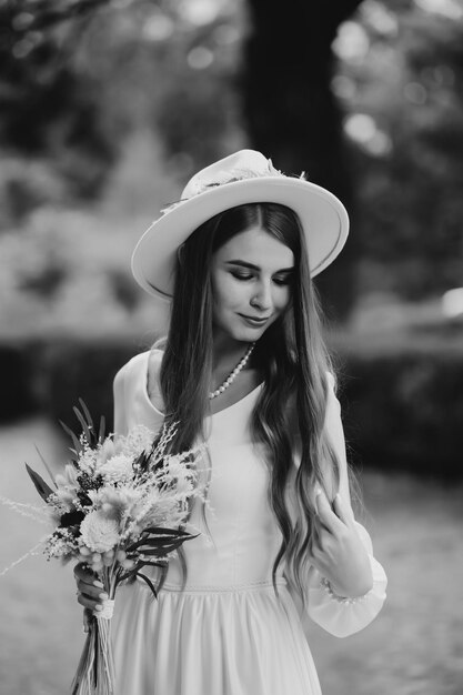 The bride in a hat and a bouquet Portrait of a bride in a white dress Portrait of the bride Young girl in a white wedding dress and hat with a bouquet of flowers