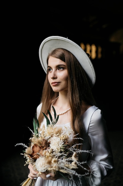 The bride in a hat and a bouquet portrait of a bride in a white\
dress portrait of the bride young girl in a white wedding dress and\
hat with a bouquet of flowers
