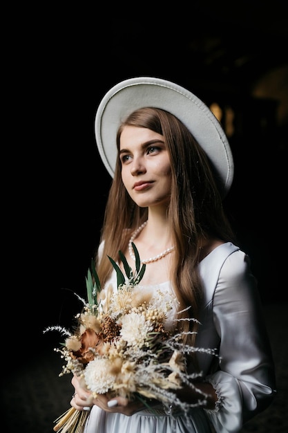 The bride in a hat and a bouquet portrait of a bride in a white\
dress portrait of the bride young girl in a white wedding dress and\
hat with a bouquet of flowers
