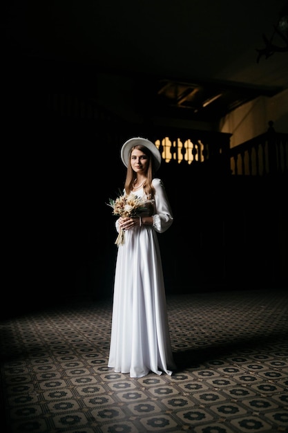 The bride in a hat and a bouquet portrait of a bride in a white\
dress portrait of the bride young girl in a white wedding dress and\
hat with a bouquet of flowers