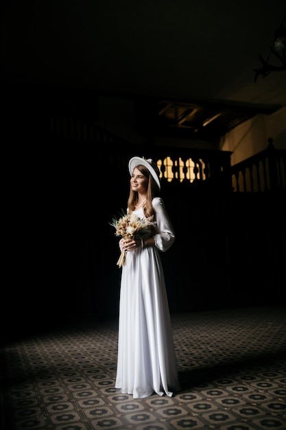 帽子と花束の花嫁白いドレスの花嫁の肖像花嫁の肖像白いウェディングドレスと花の花束の帽子の若い女の子