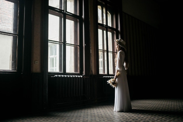 The bride in a hat and a bouquet Portrait of a bride in a white dress Portrait of the bride Young girl in a white wedding dress and hat with a bouquet of flowers