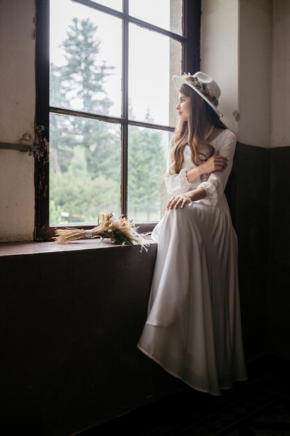 The bride in a hat and a bouquet portrait of a bride in a white\
dress portrait of the bride young girl in a white wedding dress and\
hat with a bouquet of flowers