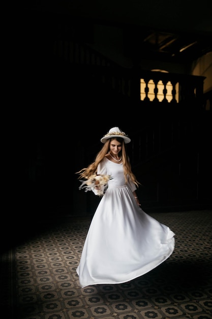 The bride in a hat and a bouquet Portrait of a bride in a white dress Portrait of the bride Young girl in a white wedding dress and hat with a bouquet of flowers