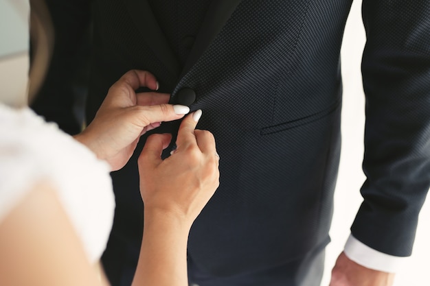 The bride helps the groom to get ready for the wedding event