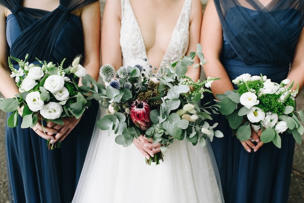 Bride and her bridesmaids holding their flower bouquets in front of them