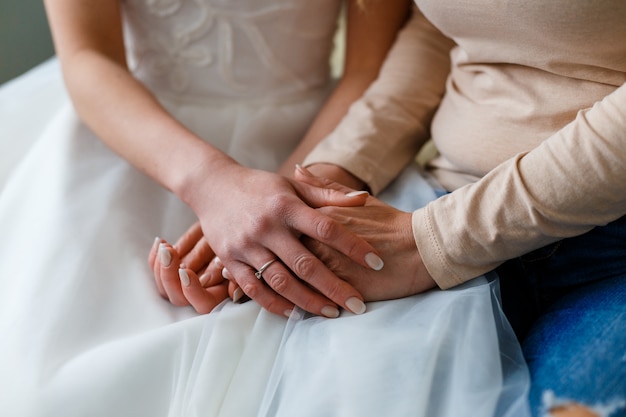 Bride on her wedding day holding her mother's hands