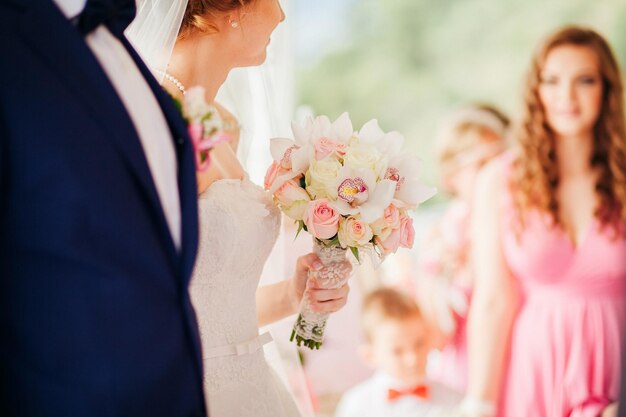 写真 花嫁はバラの蘭とバラの結婚式の花束を保持します手をクローズアップ