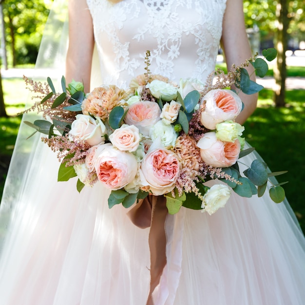 Bride holding beautiful big bouquet of roses outdoors. Square frame.
