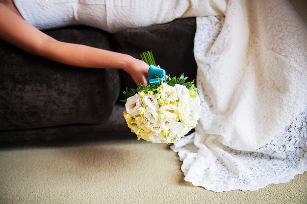 Bride holding bridal bouquet lying on the bed