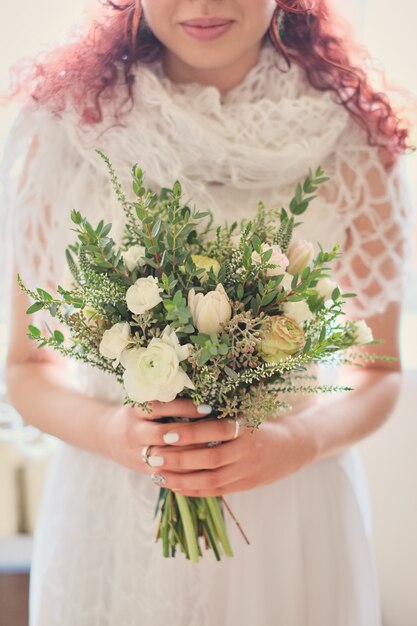 Bride holding a bright wedding bouquet with different flowers