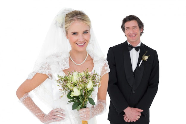 Bride holding flowers while groom standing in background