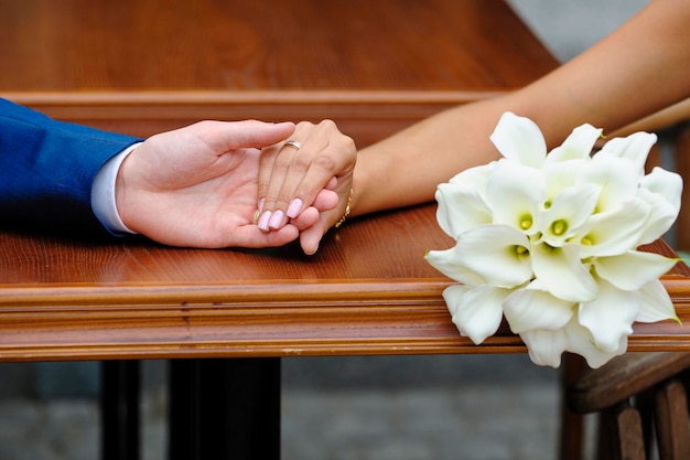 Bride holding the groom39s hand and wedding bouquet