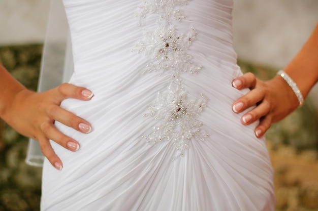 Sposa che si tiene per mano sul vestito da sposa bianco