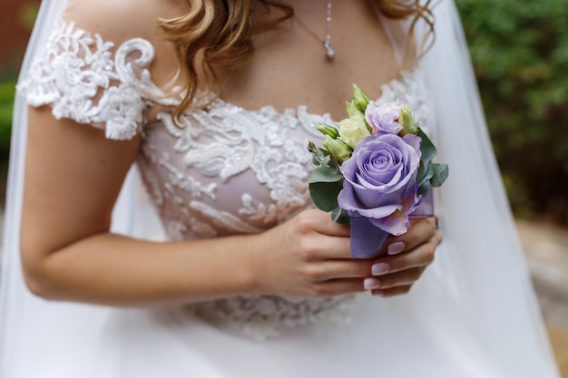 Bride holding in his hands a boutonniere vith rose of very peri colour trendy color of the year in