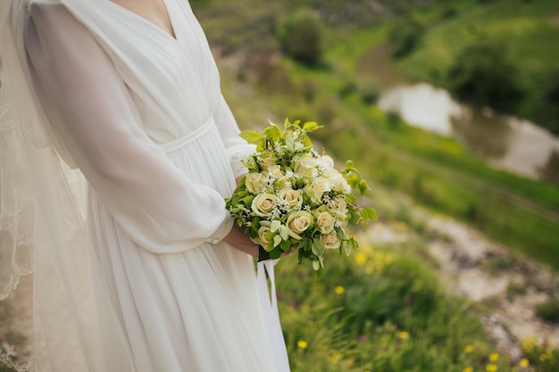 The bride holding the wedding bouquet from white roses