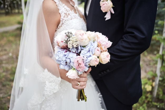 Bride holding a wedding bouquet in the hands standing near groom