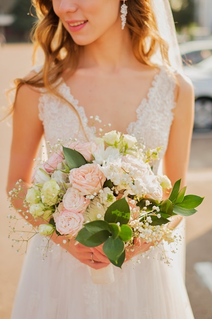 Невеста держит свадебный букет в пастельных розовых тонах. крупный план.