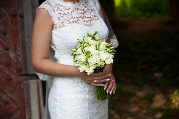 Bride holding wedding flower bouquet of roses.